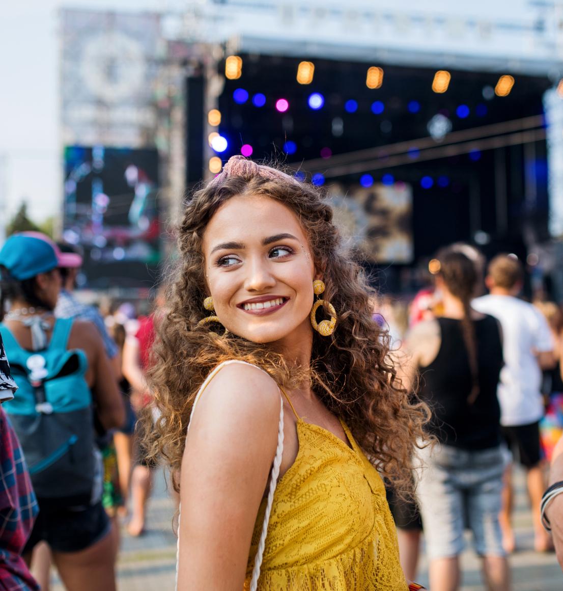 A young woman a music festival looking over her shoulders.