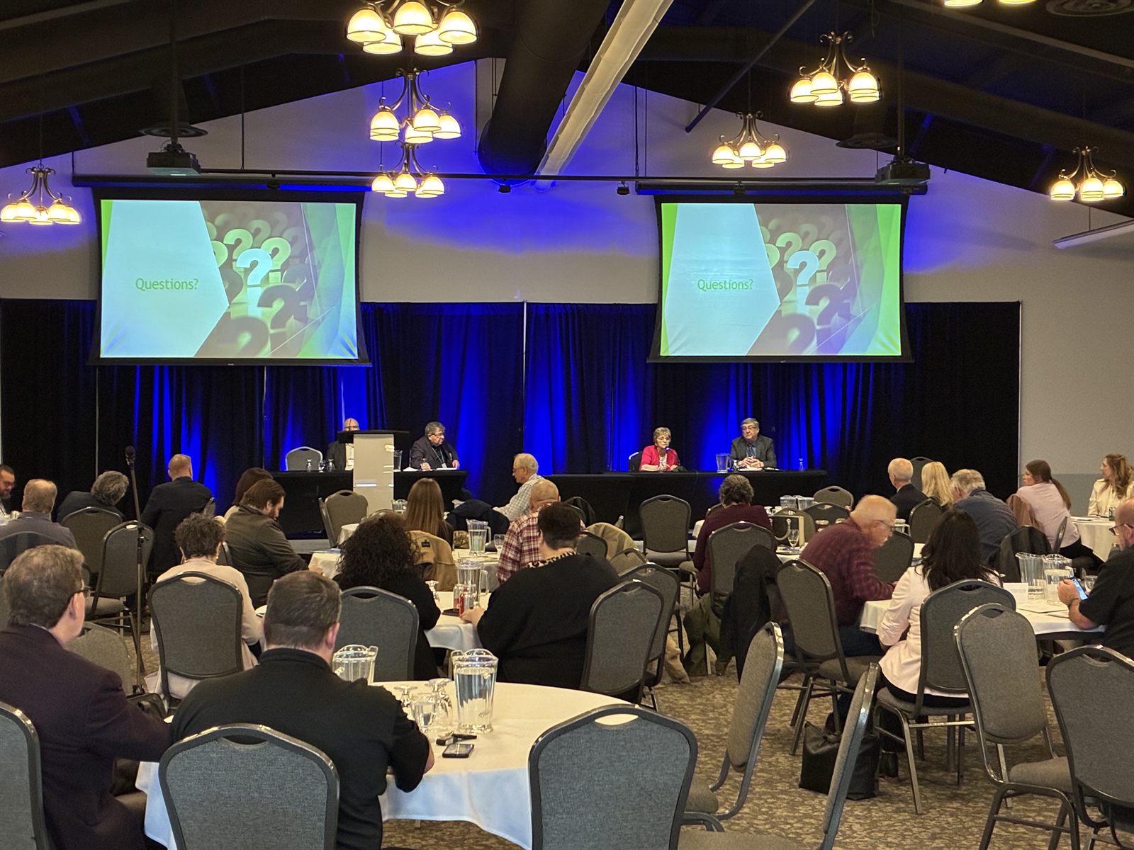 SAMA annual meeting panel discussion with attendees at round tables and Questions displayed on stage screens