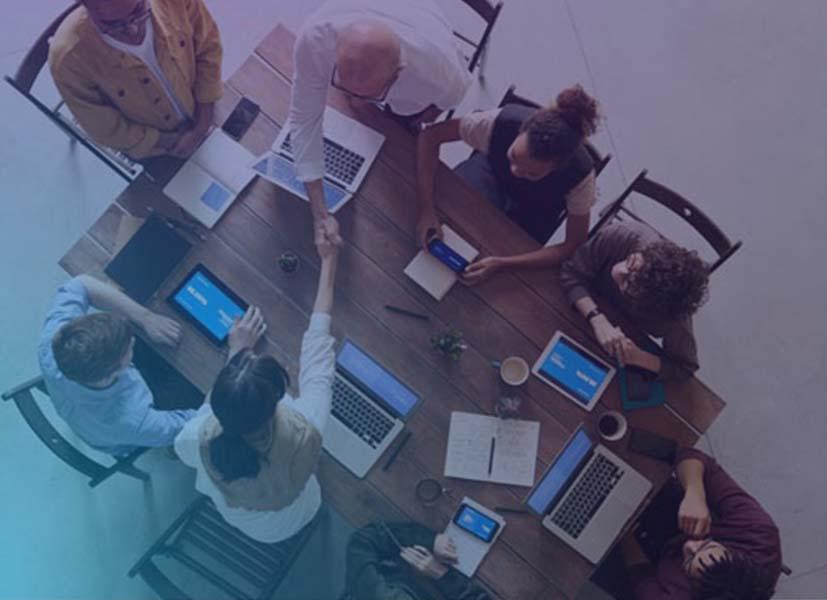 Image of a group of participant to an online seminar gathered around a meeting room table with their mobile devices.