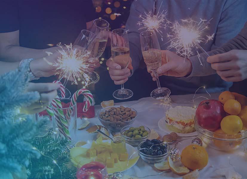Image of people toasting with champagne glasses over party snacks at a holiday event.
