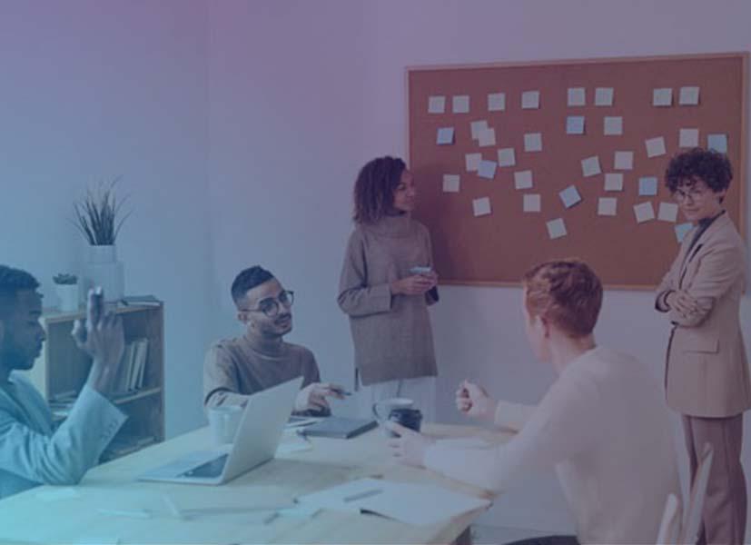 Image of a product team in a meeting room in front of a cork board with post-it notes planning a product launch event.