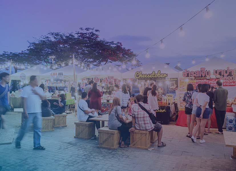 Picture of people attending a Food Festival with people lining up at food tents and others sitting down eating.